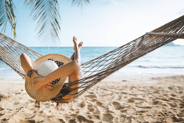 mujer asiática viajera relajarse en hamaca en la playa de verano tailandia - women summer hat beach fotografías e imágenes de stock