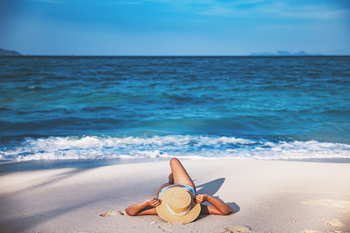 Summer travel vacation concept, Traveler asian woman with bikini and hat relax on sea beach at day in Koh Lipe, Satun, Thailand