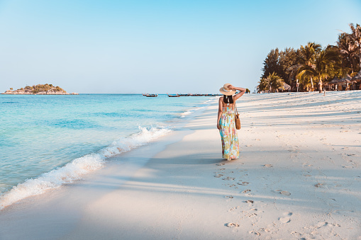 Summer travel vacation concept, Happy traveler asian woman with dress relax and sightseeing on beach in evening at Koh Lipe, Satun, Thailand,
