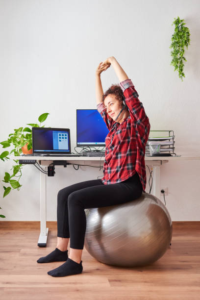 istock Woman stretches while working out sitting on a fitball 1322162426