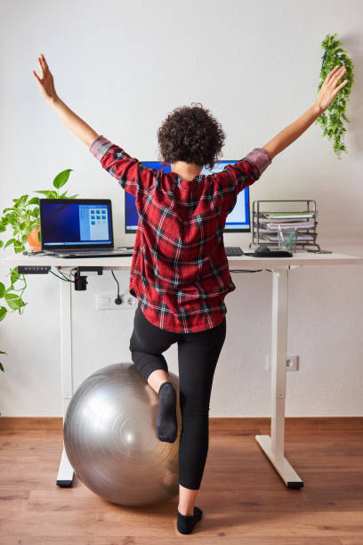 istock Woman stretches while working at an adjustable desk standing 1322162440