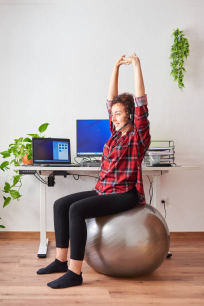 istock Woman stretches while working out sitting on a fitball 1322162447