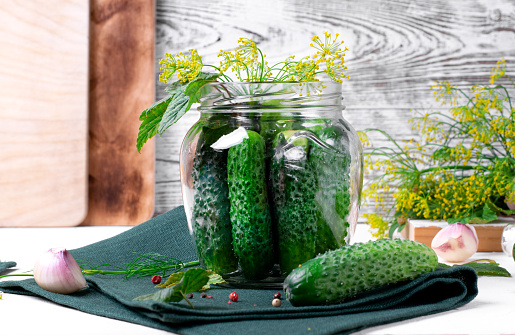 Pickling cucumbers in a glass jar on the white table. Making preserved products at home