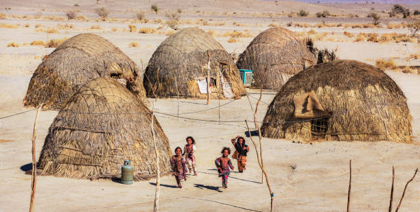 de kinderen die van baluchi naast hun traditionele huizen in de provincie van nik shahr, sistan en baluchestan, iran spelen. - nouri stockfoto's en -beelden