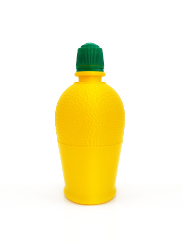 Close up of Bottle of squeezed lemon juice dressing. Lemon juice in an open bottle on a white background. Yellow plastic container and green cap. Plastic bottle of lemon juice to the sauce isolated.