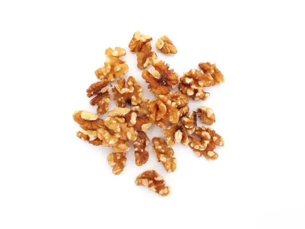 Aerial view of peeled walnuts on white background. Isolated bulk organic shelled walnuts. Pieces of Nuts. Organic and healthy food.