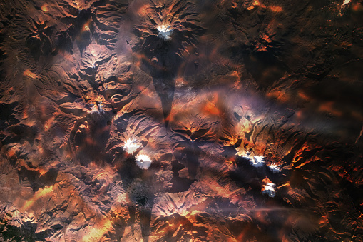 Collage with red lava reflections of several snow- and ice-capped volcanoes over a mountainous region of Bolivia and Chile. The elements of this image furnished by NASA.

/nasa urls used for this collage:
https://visibleearth.nasa.gov/images/146301/nevado-sajama-and-parinacota/146303l
https://images.nasa.gov/details-PIA22692.html
https://eoimages.gsfc.nasa.gov/images/imagerecords/91000/91578/CrevassedGlacier1_dms_2017301_lrg.JPG 
(https://earthobservatory.nasa.gov/images/91578/signs-of-flow-atop-antarctic-ice)