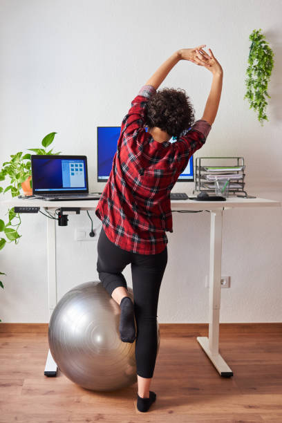 istock Woman stretches while working at an adjustable desk standing 1322169431