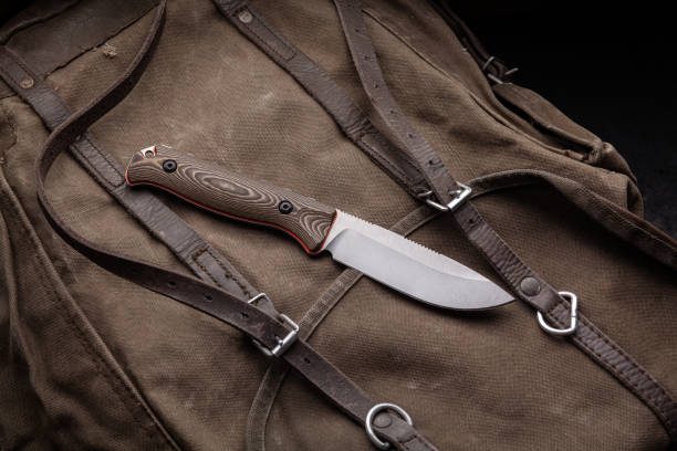 istock A hunting knife with a wooden handle on a khaki canvas backpack. Weapons for self-defense and survival. 1322171599