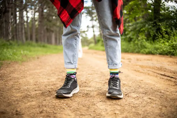 A woman standing in nature, in rainbow-colored socks, the LGBT population..