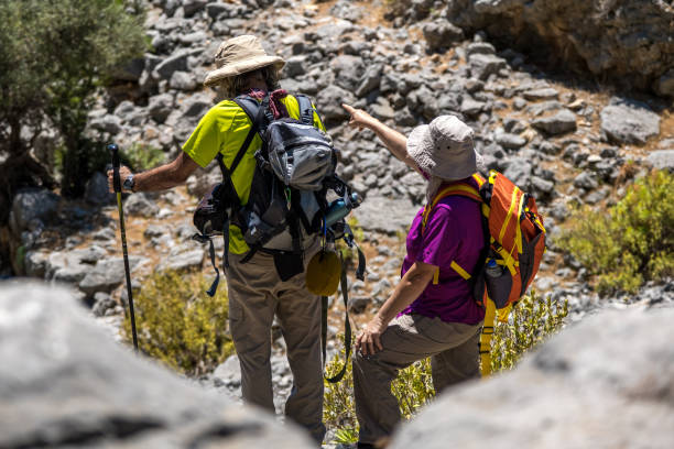 istock Elderly backpacker couple contemplating direction over a high boulder 1322176425