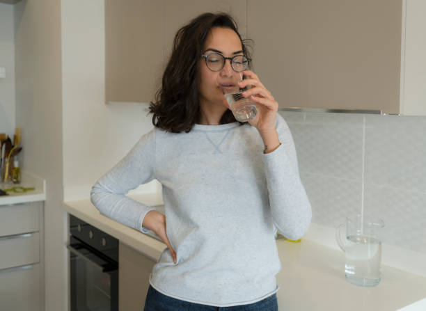 istock Young woman in the kitchen drinking water 1322177631