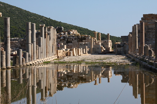 Antalya, Turkey-April 25, 2013: Port ruins in Patara Ancient City, Columns reflected in water.