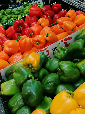 Bell peppers in all variations, red bell pepper, orange bell pepper, green bell pepper and yellow bell pepper for sale on a market in Mexico.