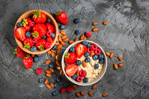 Tasty granola with fresh berries and spoon on brown wooden background