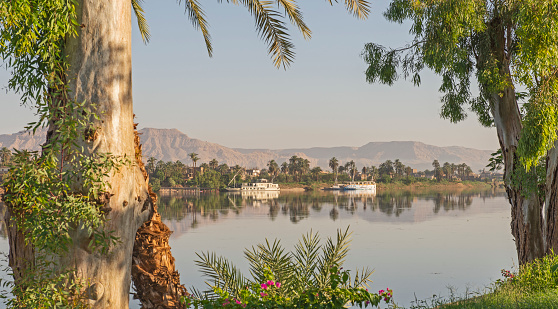 Panoramic landscape view across nile river to luxor west bank with mountains and reflection in water