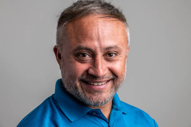 istock Smiling mature hispanic man looking at the camera on gray background 1322183604