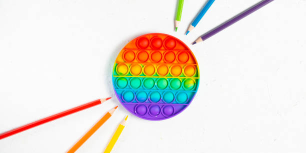 istock Rainbow silicone antistress pop it or simplele simple with multicolored pencils on white background 1322185972