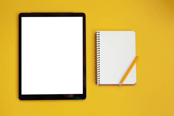 istock Tablet screen mockup and notepad isolated on yellow background, top view 1322192234