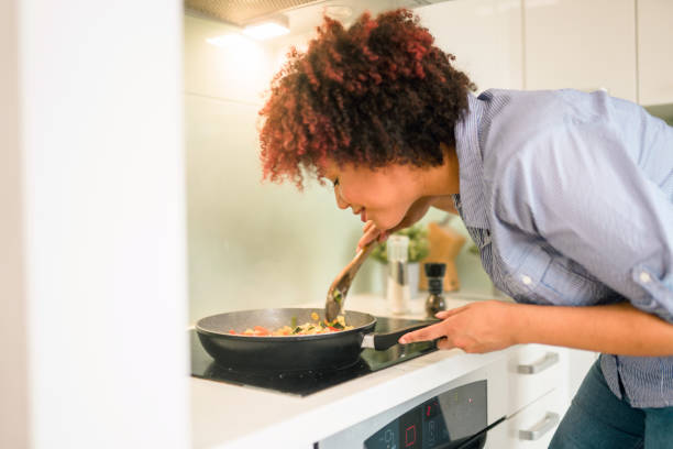 istock Beautiful Mixed Race Female Smelling Food While Cooking 1322193390