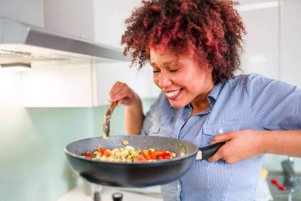 istock Beautiful Mixed Race Female Smelling Food While Cooking 1322193396