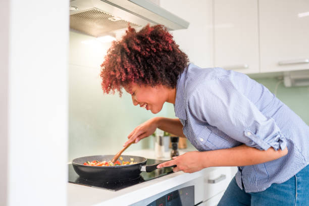 istock Beautiful Mixed Race Female Smelling Food While Cooking 1322193401