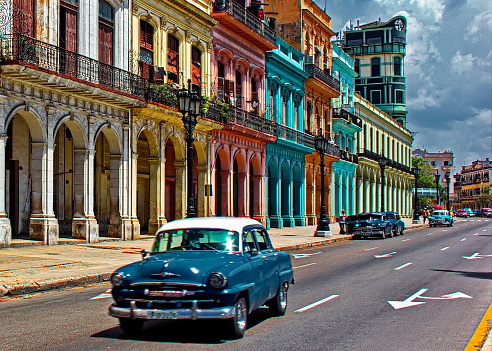 Blue American Vintage Car on main Havana street, in front of historic buildings, Cuba