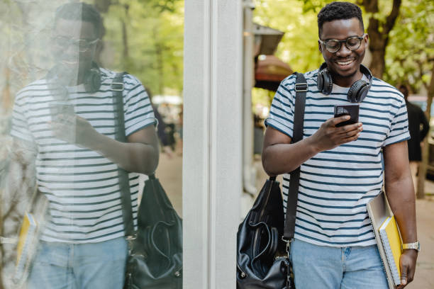 istock African-American confident young man is using mobile phone on the street 1322199170