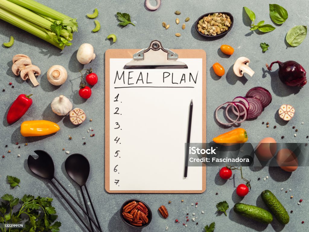 Meal plan concept. Hard light Meal plan concept. Food ingredients, salad serving utensils and clipboard with letters MEAL PLAN and seven numbers. Gray background. Diet menu concept. Top view, flat lay Menu Stock Photo