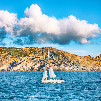Splendid view of sailboat sailing near the cliffs of  Santa Teresa Gallura. Popular travel destination of Mediterranean sea. Location: Santa Teresa Gallura, Province of Sassari, Sardinia, Italy, Europe