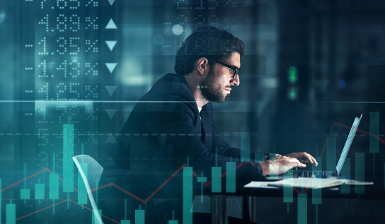 Foto mejorada digitalmente de un guapo hombre de negocios usando una computadora portátil superpuesta sobre un gráfico que muestra los altibajos del mercado de valores photo