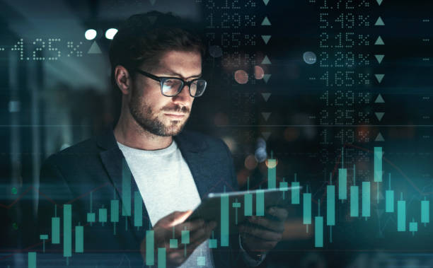 istock Digitally enhanced shot of a handsome businessman using a tablet superimposed over a graph showing the ups and downs of the stock market 1322205519