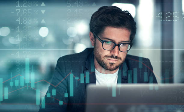 istock Digitally enhanced shot of a handsome businessman using a laptop superimposed over a graph showing the ups and downs of the stock market 1322205562