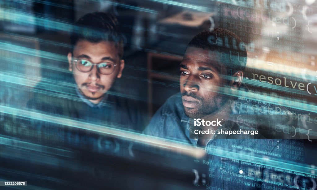 Digitally enhanced shot of two handsome businessmen working in the office superimposed over multiple lines of computer code Tonight's task in the hands of the team Technology Stock Photo