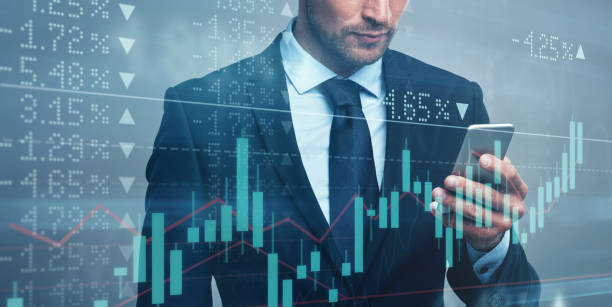 istock Digitally enhanced shot of an unrecognizable businessman using a cellphone superimposed over a graph showing the ups and downs of the stock market 1322205583