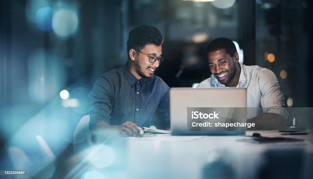 Cropped shot of two young businessmen working together on a laptop in their office late at night The dream will be ours by the end of tonight Technology Stock Photo