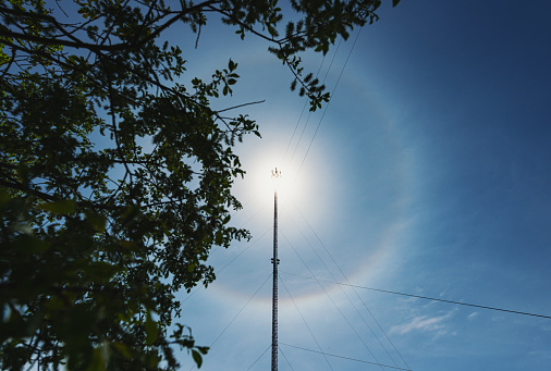 A cellular/data tower beneath a solar halo.