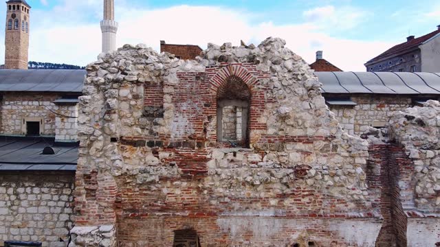 Drone with camera flies away from dilapidated window in wall of ruins of ancient Taslihan caravanserai in Sarajevo. Explore sights of old European town. Travel blog