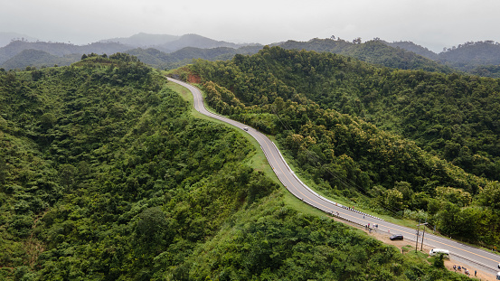 Aerial view of curve road through green forest and mountain rural scene north of Thailand