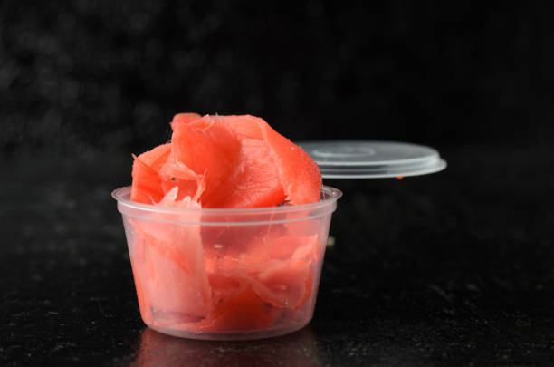 istock Ginger root chopped into thin slices of red color in a delivery plastic jar. 1322227255