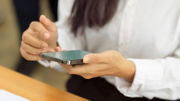 istock Female hands using smartphone, texting message on the phone in workplace 1322230266
