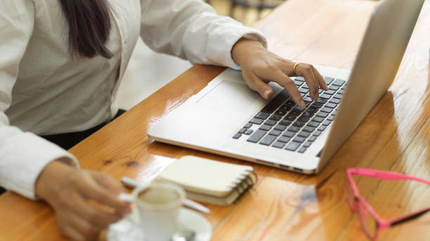istock Businessperson hand working with laptop and holding coffee cup on workspace 1322230413