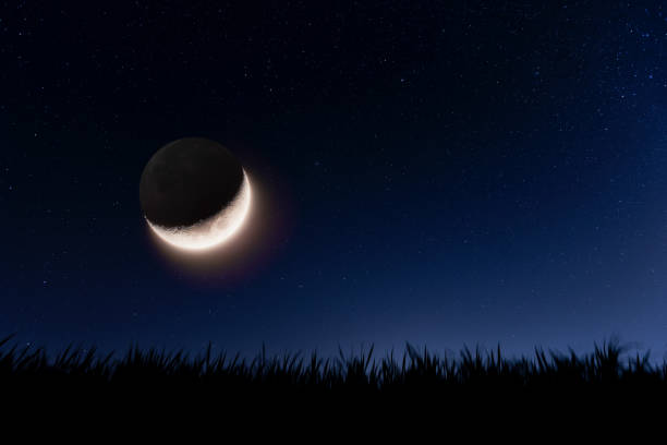 Earthshine phenomenon It is a phenomenon caused by sunlight reflected on the surface of the earth to the moon with starry sky and field grass