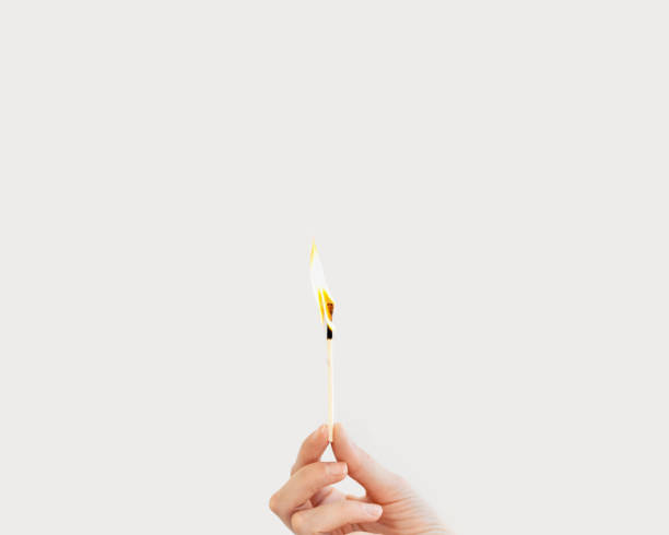 Woman hand holds lit match. Wooden matchstick is burning. Fire Hazard concept. Woman hand holds lit match on white background. Wooden matchstick is burning. Fire Hazard concept. lit match stock pictures, royalty-free photos & images