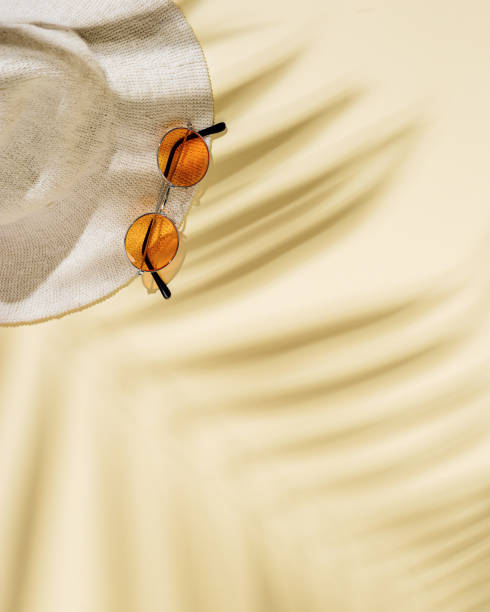 istock Summer beach rest concept background with hat, colored sunglasses  with palm tree shadows. Flat lay with woman accessory 1322235523