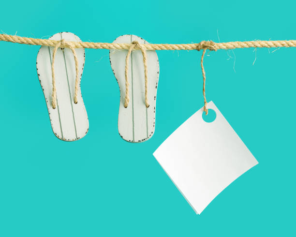 ummer minimal composition with slipper or flip-flop and white paper hanging on rope