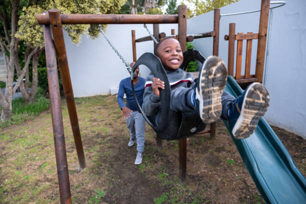 istock Little boy being pushed on the swing by his dad 1322239058