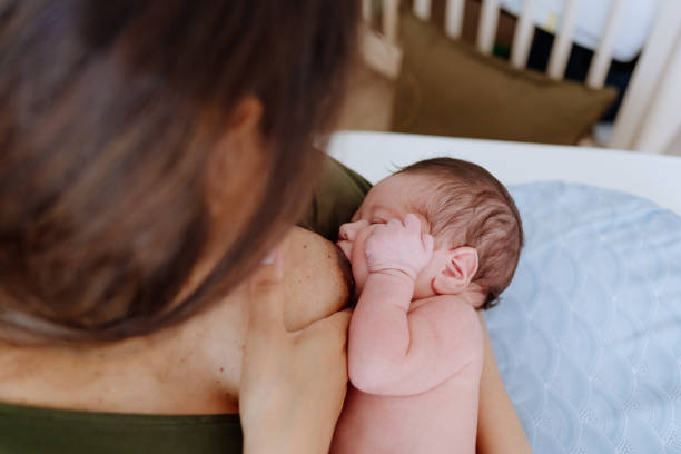 Mother breastfeeding her baby boy in the nursery room stock photo