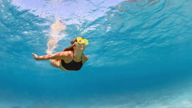 Girl in snorkeling mask dive underwater in blue sea lagoon Young girl in snorkeling mask dive in coral reef sea lagoon to explore underwater world. Family travel lifestyle in summer adventure camp. Swimming activities on beach vacation with kids. snorkel photos stock pictures, royalty-free photos & images