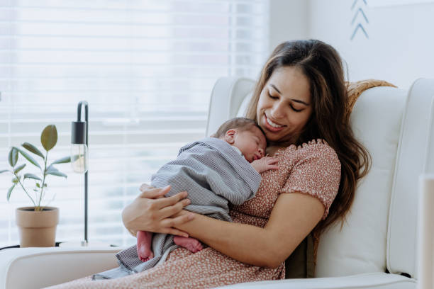 Mother holding her baby boy in the nursery room stock photo